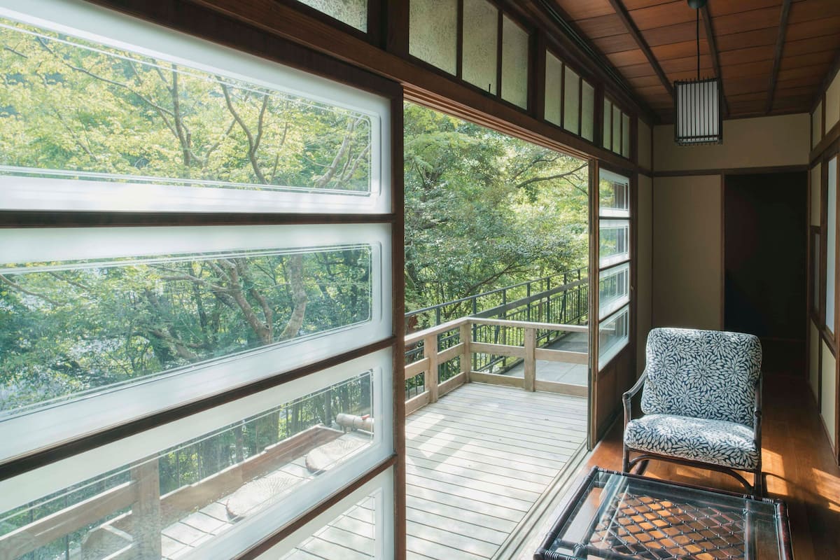 A room with large windows, a wooden deck, and a patterned chair.