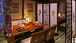 A traditional Japanese dining room with tatami mats, a low wooden table set with dishes, and sliding doors.