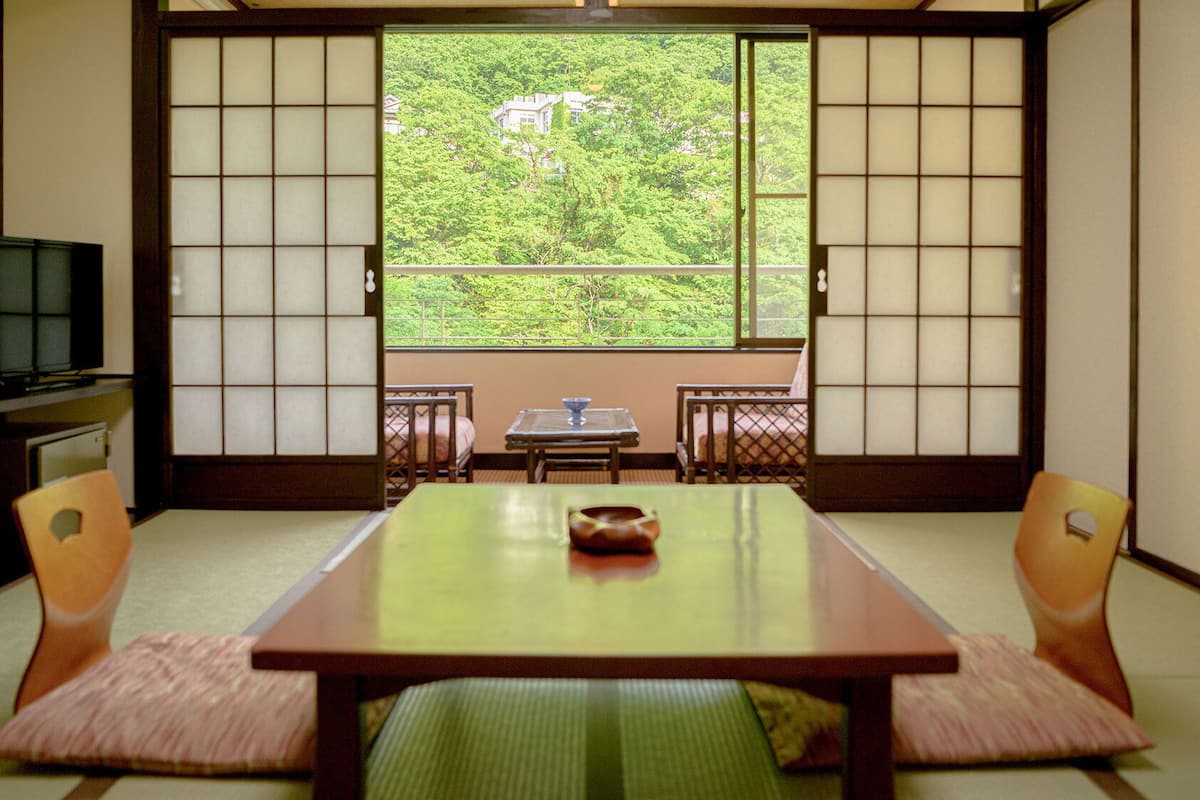 Una habitación japonesa tradicional con suelo de tatami, una mesa baja y puertas correderas shoji.