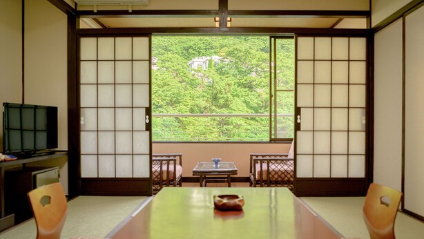 A traditional Japanese room with tatami flooring, a low table, and sliding doors.