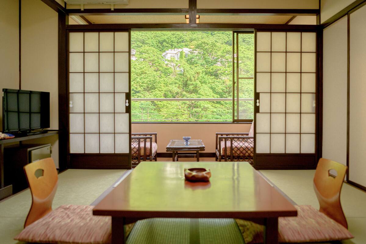 Una habitación japonesa tradicional con suelo de tatami, una mesa baja y puertas correderas.
