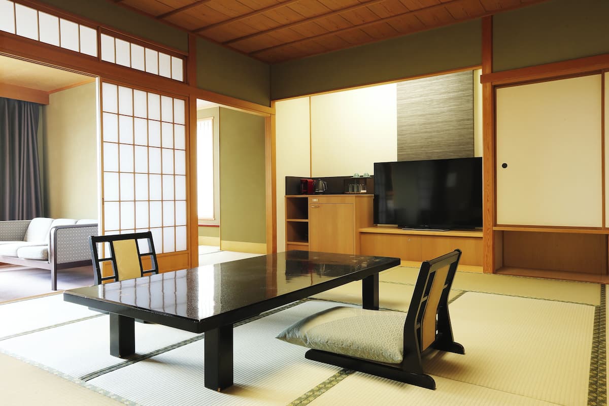Une pièce de style japonais traditionnel, avec un sol recouvert de tatamis, une table basse, un téléviseur et des portes coulissantes.