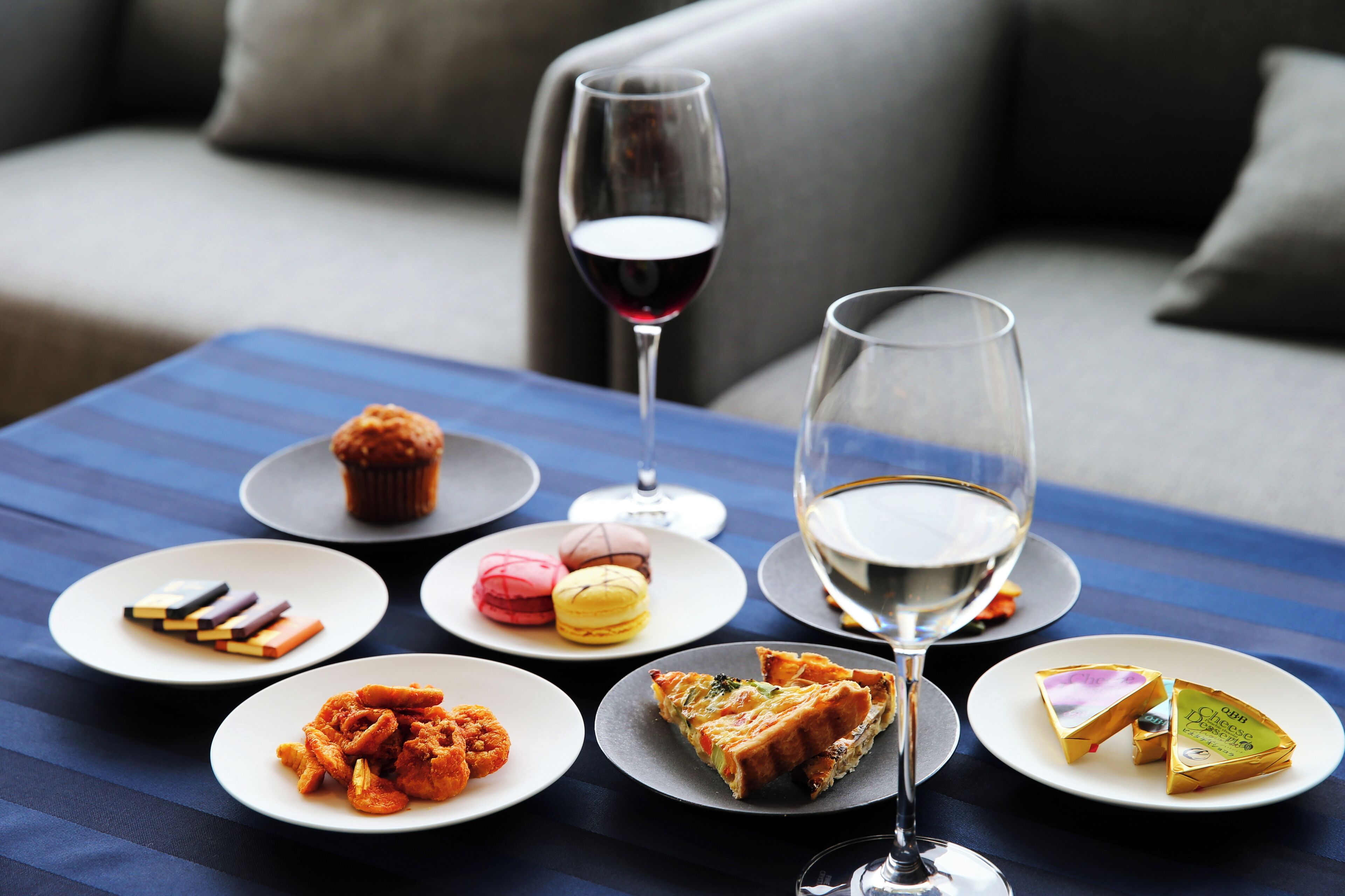 Una mesa de comedor con diversos platos, copas de vino y un sofá al fondo.