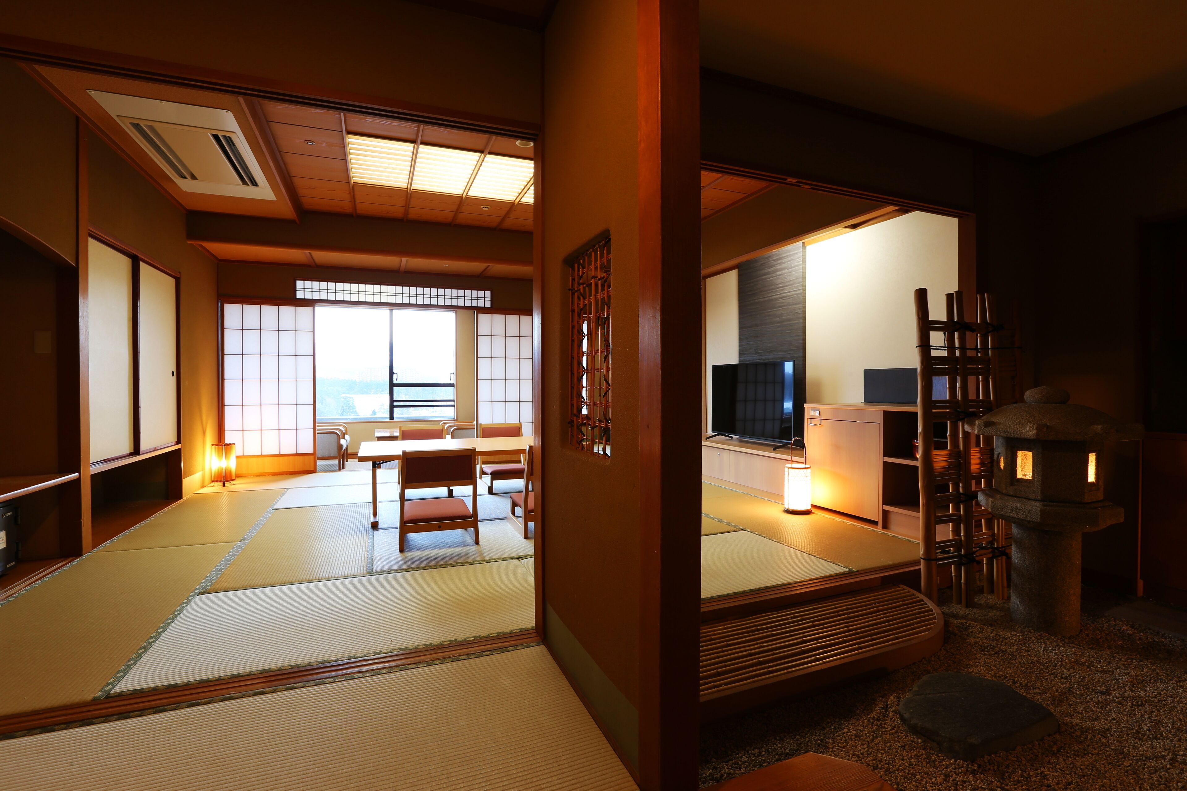 A traditional Japanese room with tatami flooring, a tatami mat table, a low wooden table, and a built-in fireplace.