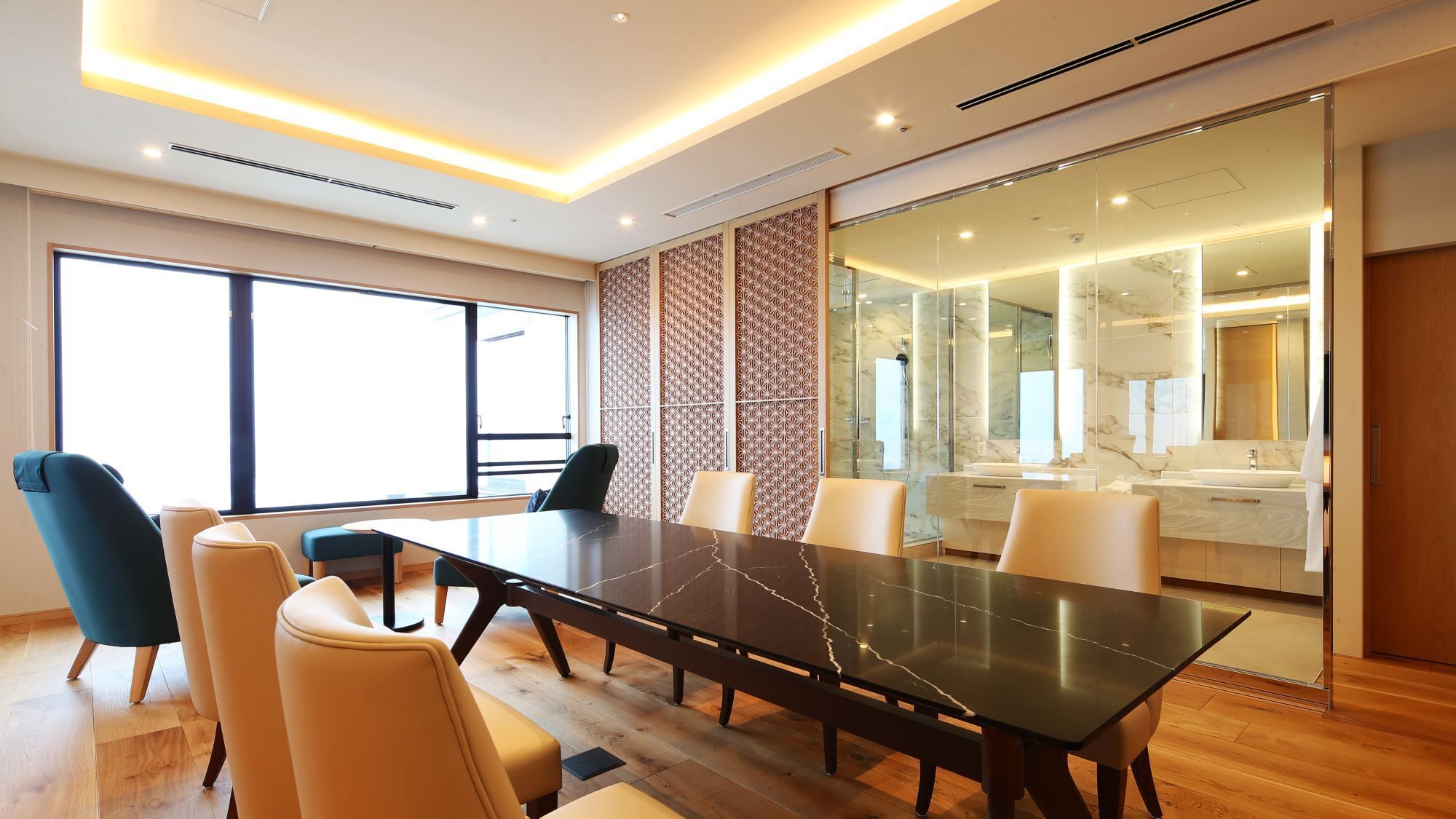 A modern conference room with a marble table, leather chairs, a large window, and a glass partition leading to a bathroom.