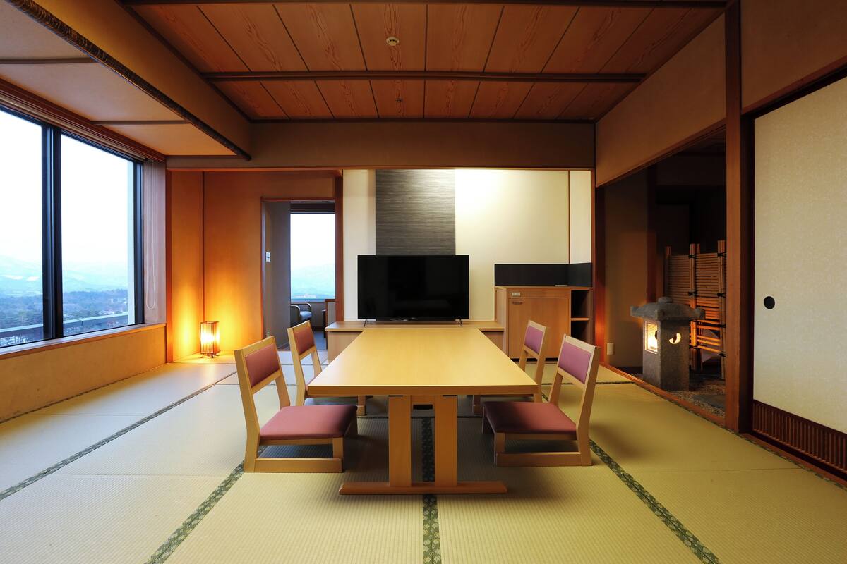 Une pièce de style japonais traditionnel, avec un sol recouvert de tatamis, une basse table en bois et des chaises rembourrées de couleur rouge.