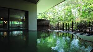 Un área de piscina interior tranquila con una pared de vidrio que refleja la vegetación circundante.