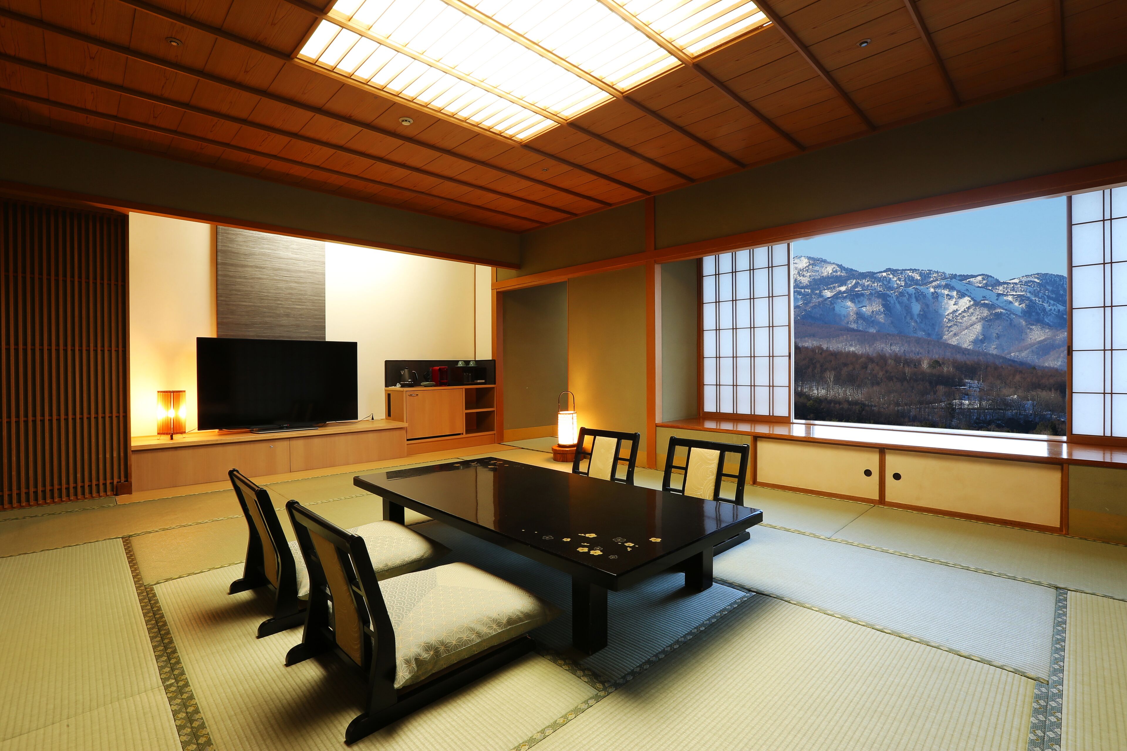 A traditional Japanese room with tatami flooring, a low table, and a television.