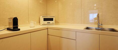 Una cocina moderna con microondas integrado, cafetera y lavabo.