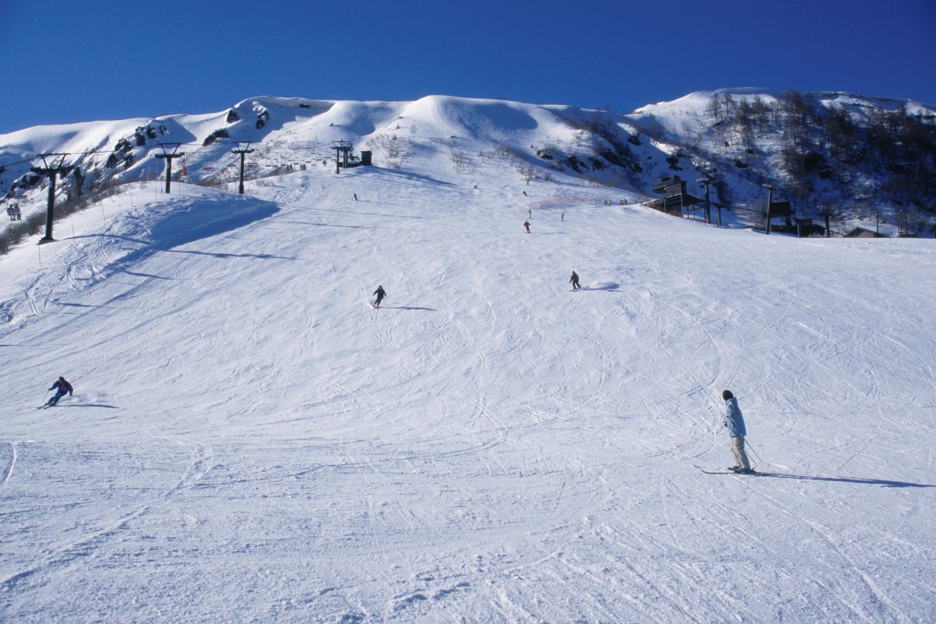 A snowy ski slope with skiers and a ski lift.