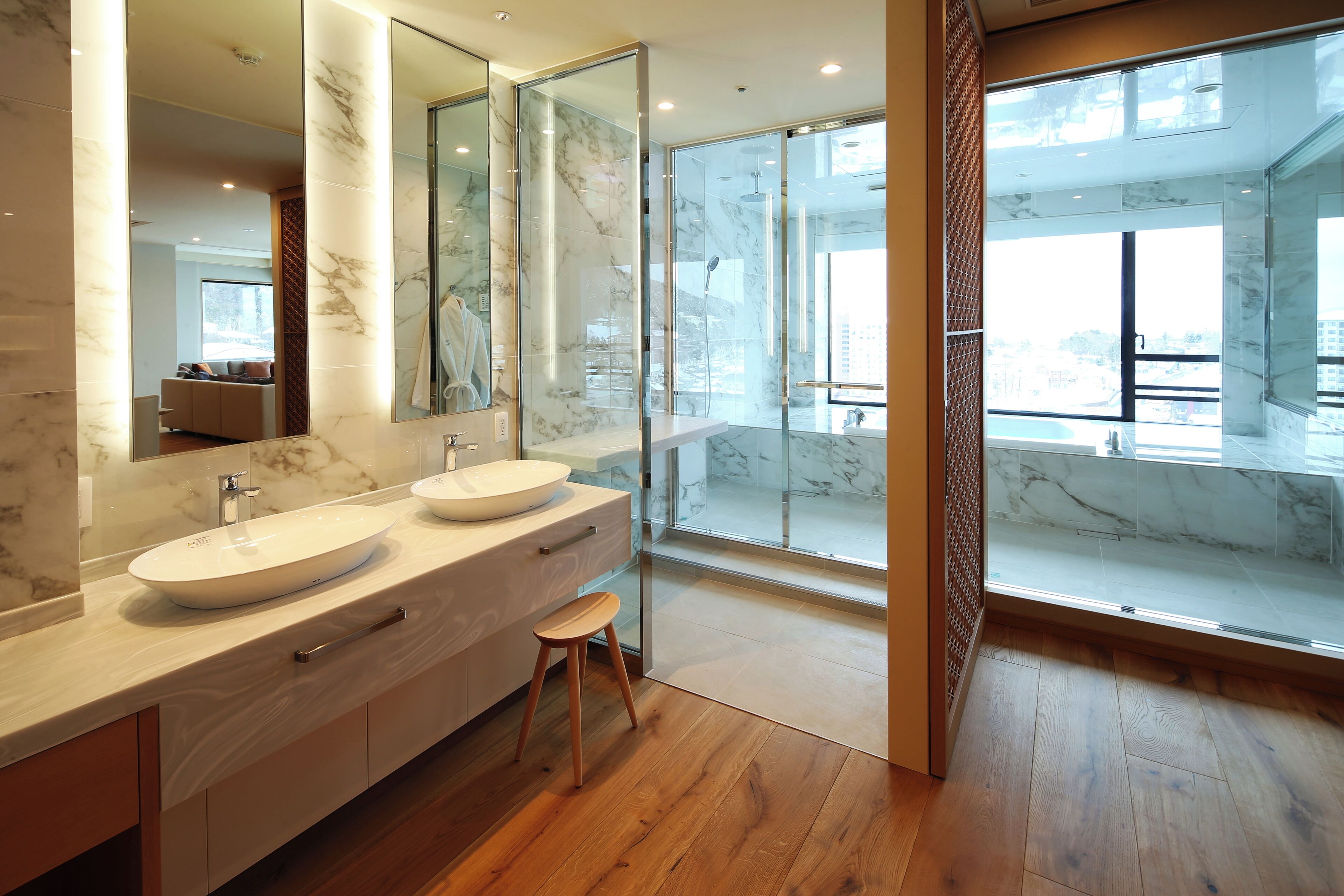 Ein modernes Badezimmer mit zwei Waschbecken, einem großen Spiegel und einer Duschkabine aus Glas.