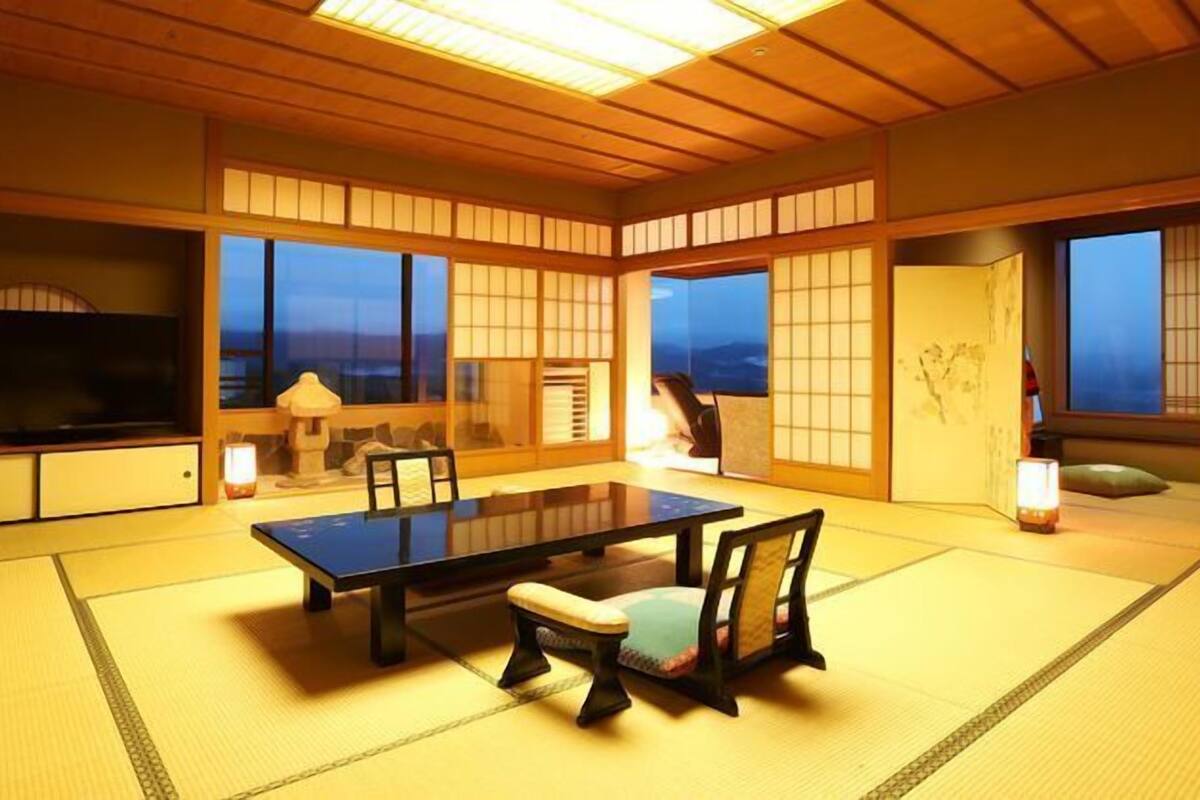 Une pièce de style japonais traditionnel, avec un sol recouvert de tatamis, une table basse et des chaises.