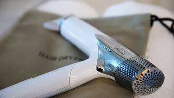 A hair dryer with a metallic nozzle and a white body, placed on a beige surface.