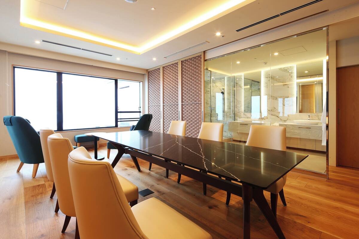Une salle de réunion moderne, dotée d’une grande table, de chaises confortables et d’une cloison en verre.