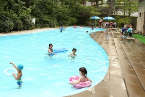 A swimming pool with people in the water and on the deck. - Kusatsu Onsen Hotel Sakurai (Kusatsu)