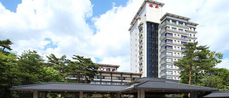 Un hotel de estilo arquitectónico japonés tradicional, que presenta un edificio grande con varios pisos y un prominente emblema rojo en la parte superior.