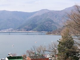 Vista de un lago con barcos, un puente y montañas al fondo.