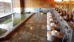 Un baño público con una bañera grande, varios lavamanos con espejos y suelo de baldosas.