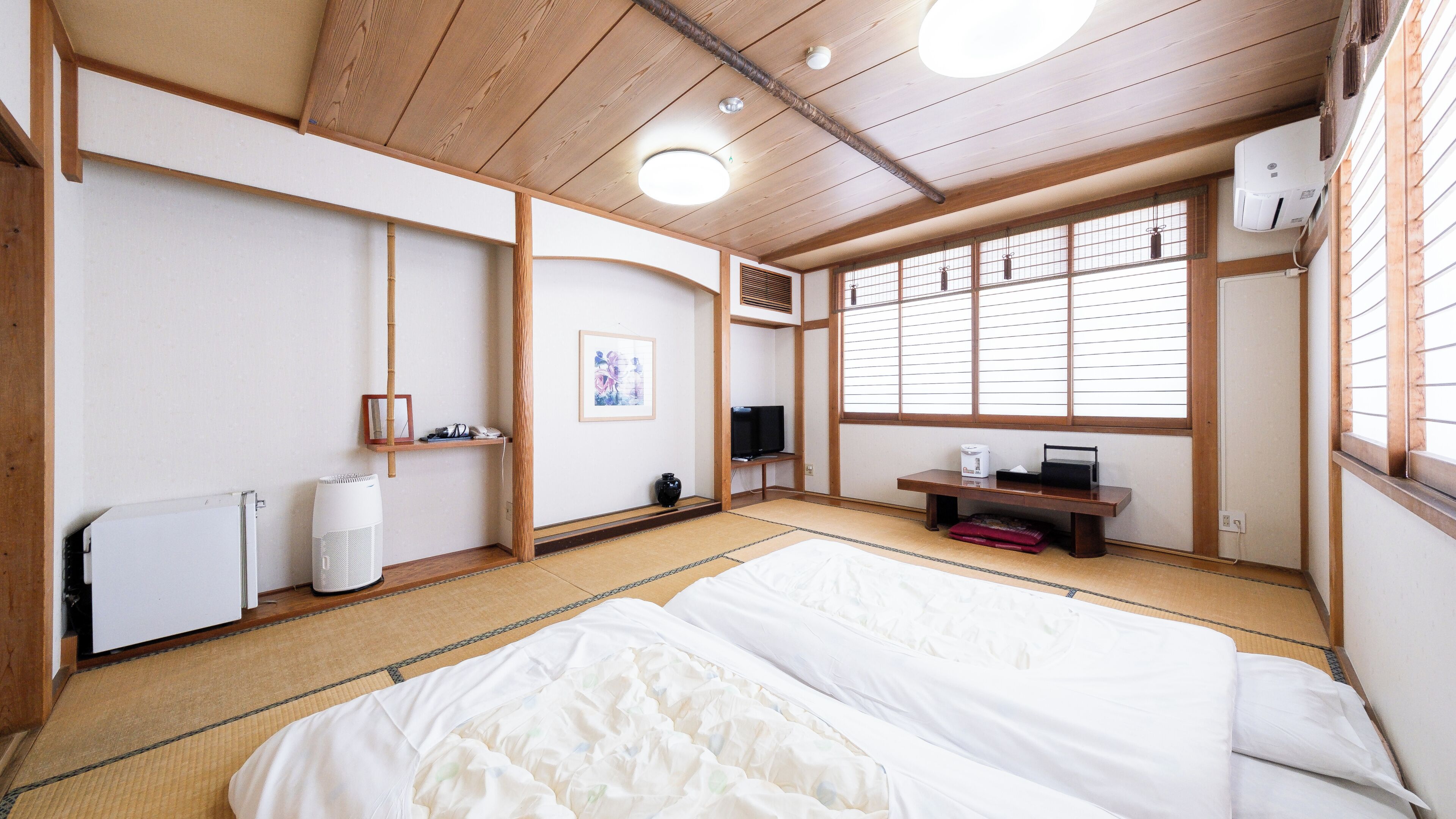 Habitació japonesa tradicional amb sòls de tatami, un llit, una televisió i un calefactor.