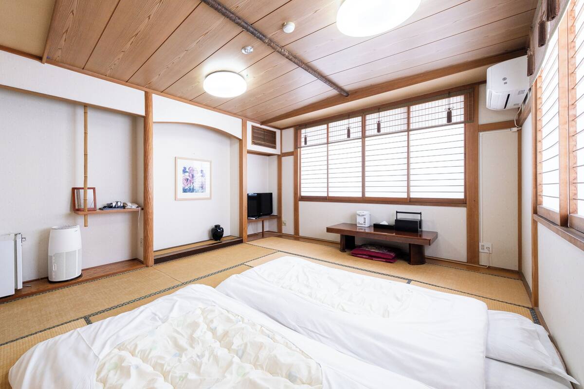 Una habitación tradicional japonesa con suelo de tatami, cama, televisor y calefacción.