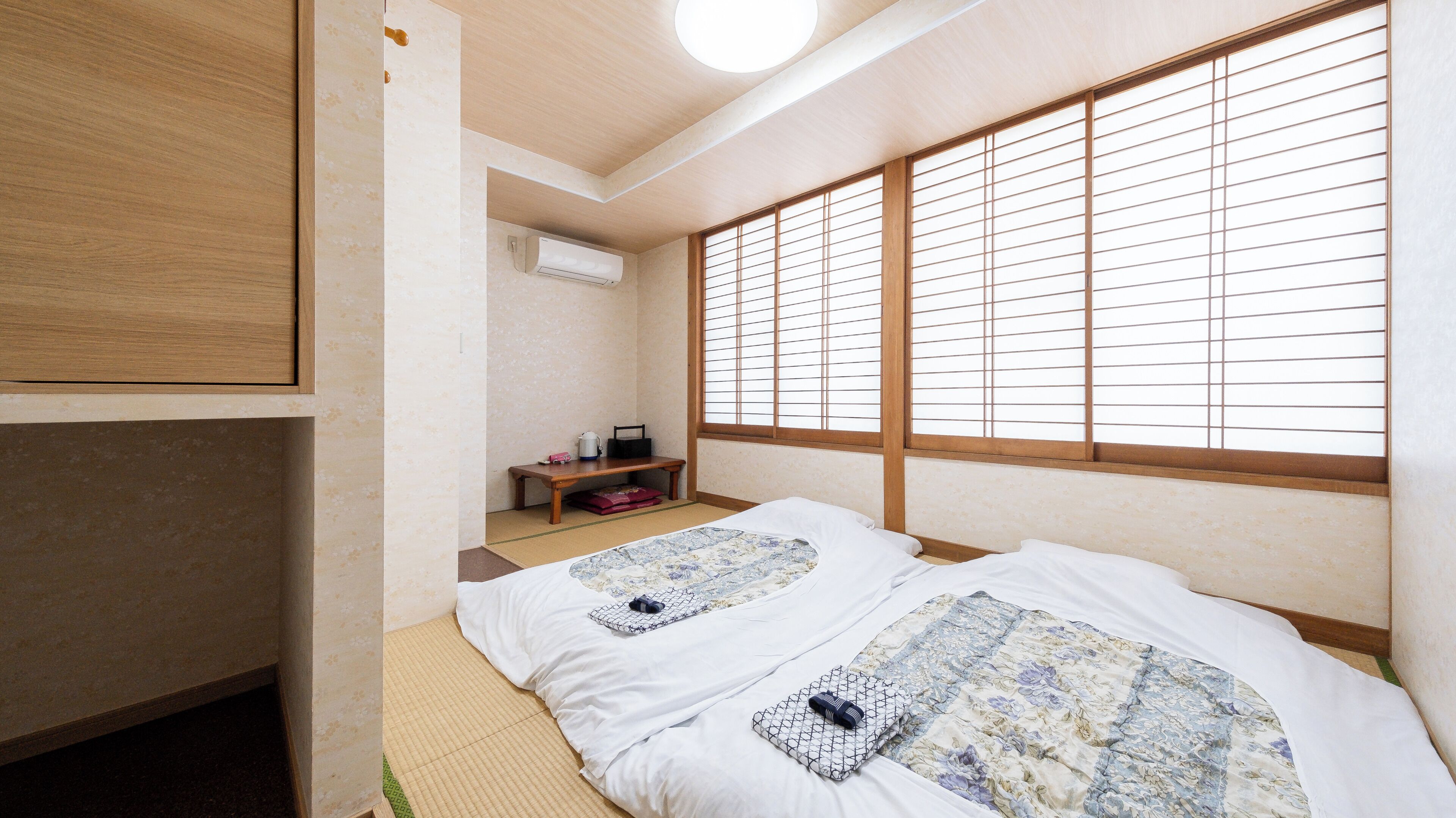 Una habitació tradicional japonesa amb tatami, un llit futon, una taula petita amb búllet i portes corredisses shoji.
