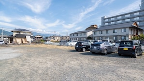 A parking lot with multiple cars and residential buildings in the background. - Fujizakura Onsen Ryokan (Fuefuki)