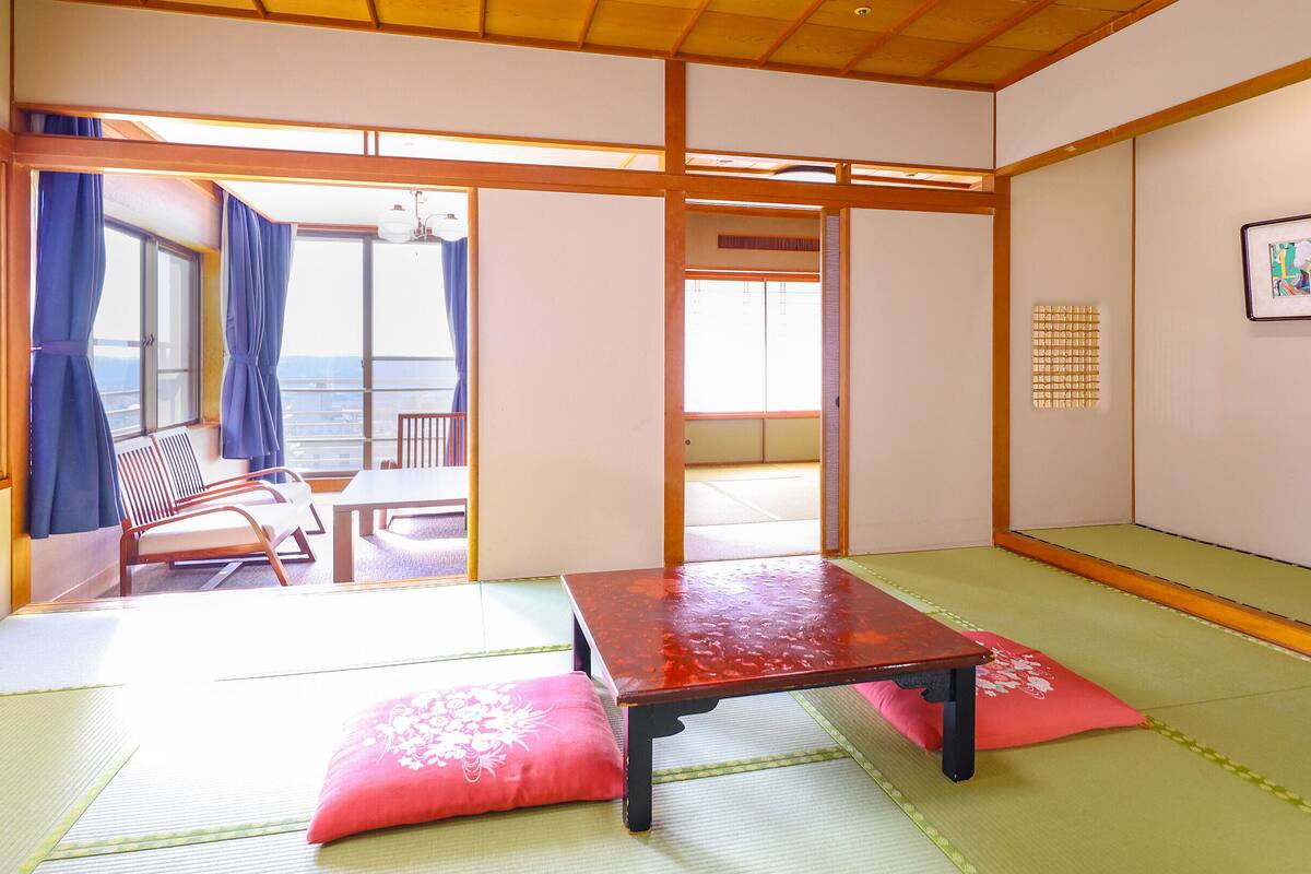 A traditional Japanese room with tatami flooring, a low table, and a view of the outside.