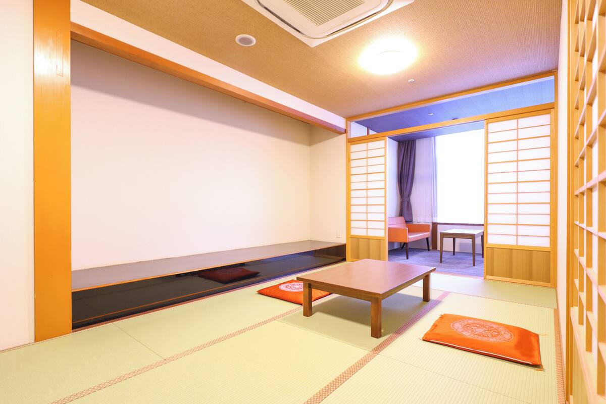 A traditional Japanese room with tatami flooring, a low table, and sliding doors.
