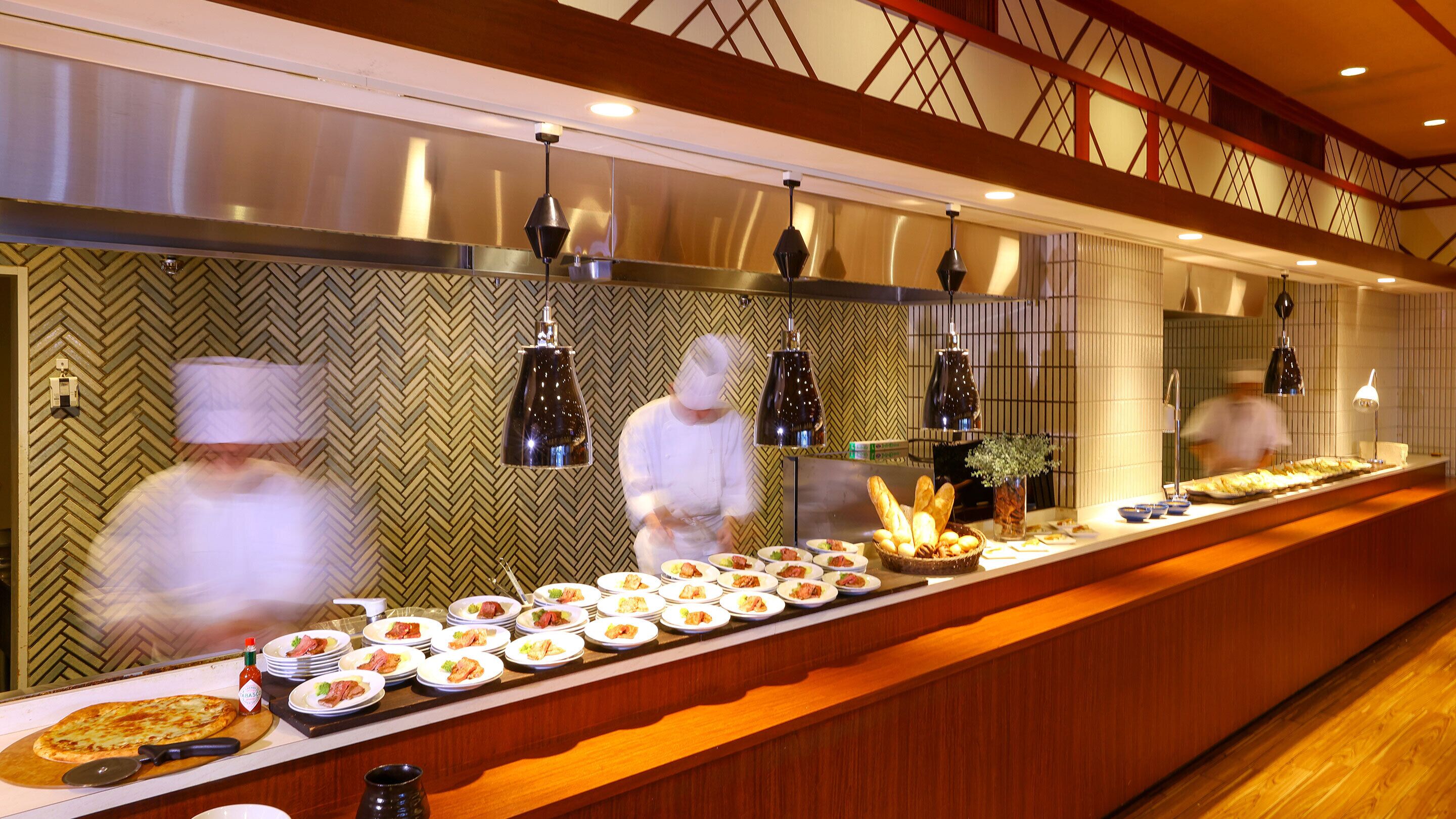 A buffet setup with various dishes and a chef preparing food.