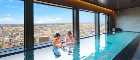An indoor swimming pool with large windows offering a city view.