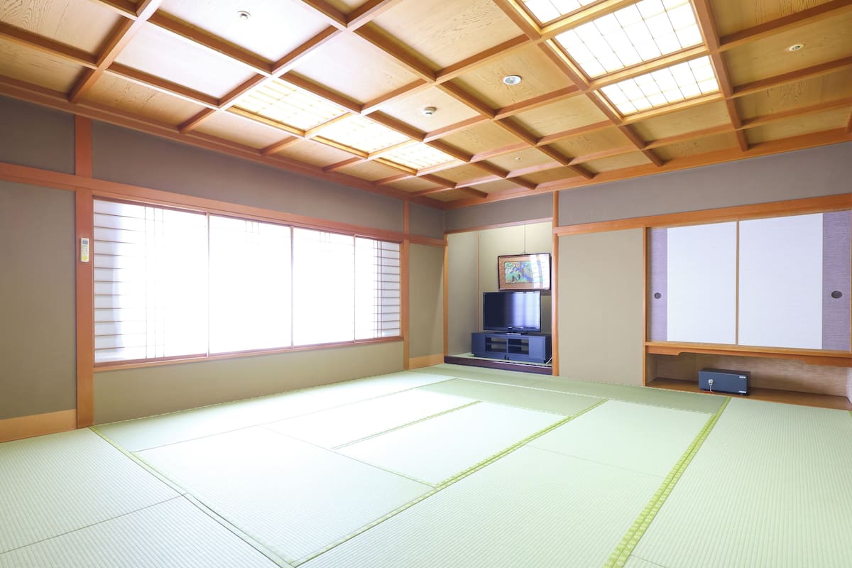 A traditional Japanese room with tatami flooring, sliding doors, and a television.