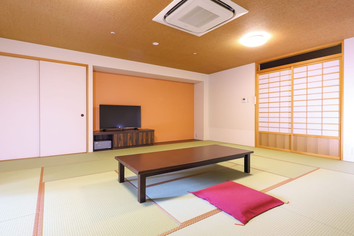 A traditional Japanese room with tatami flooring, a low table, and sliding doors.