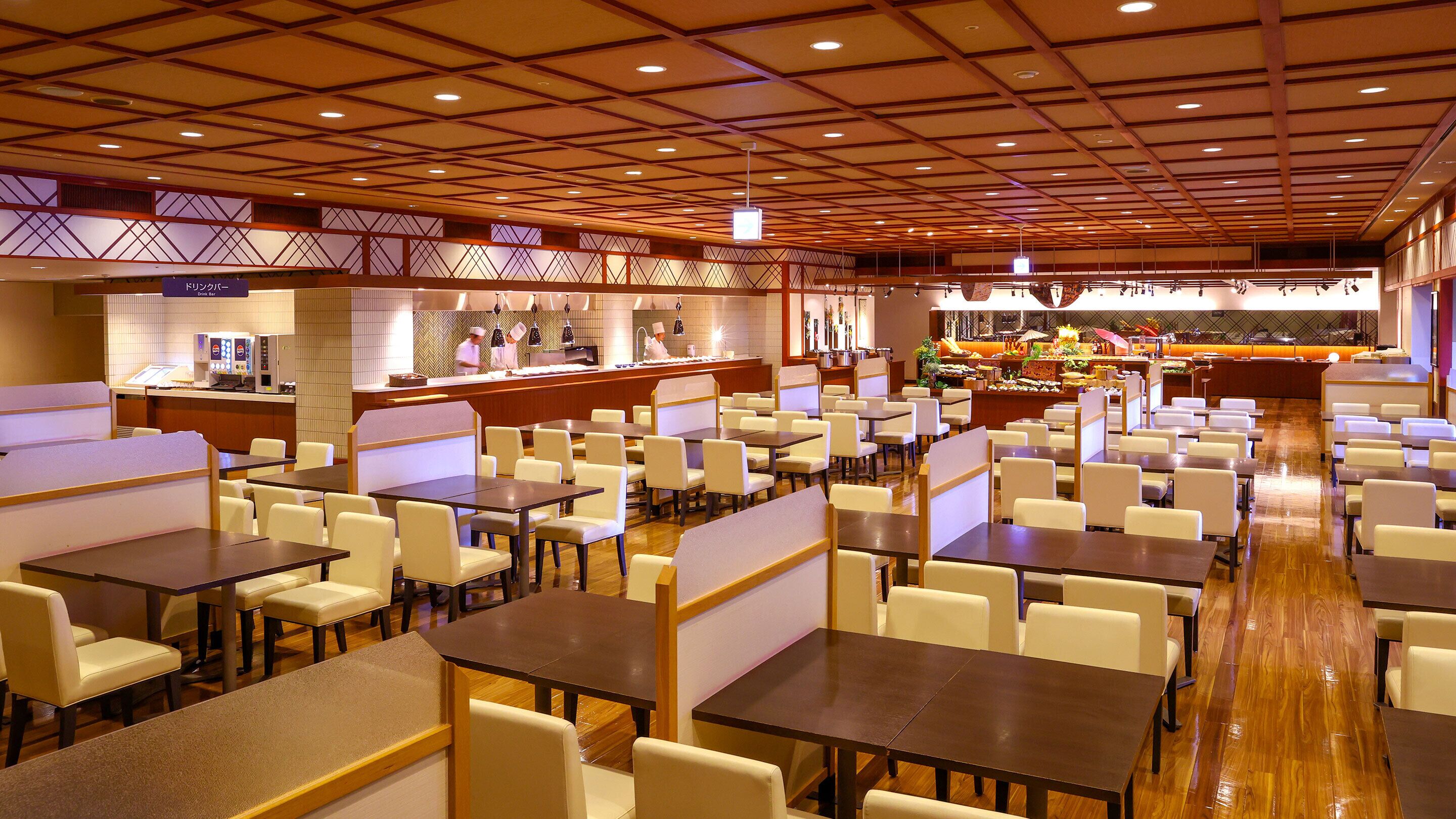 Un restaurante amplio con varias áreas de comedor, un bar central y un bufé.
