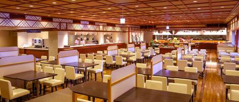 Un restaurante amplio con varias áreas de comedor, un bar central y un bufé.