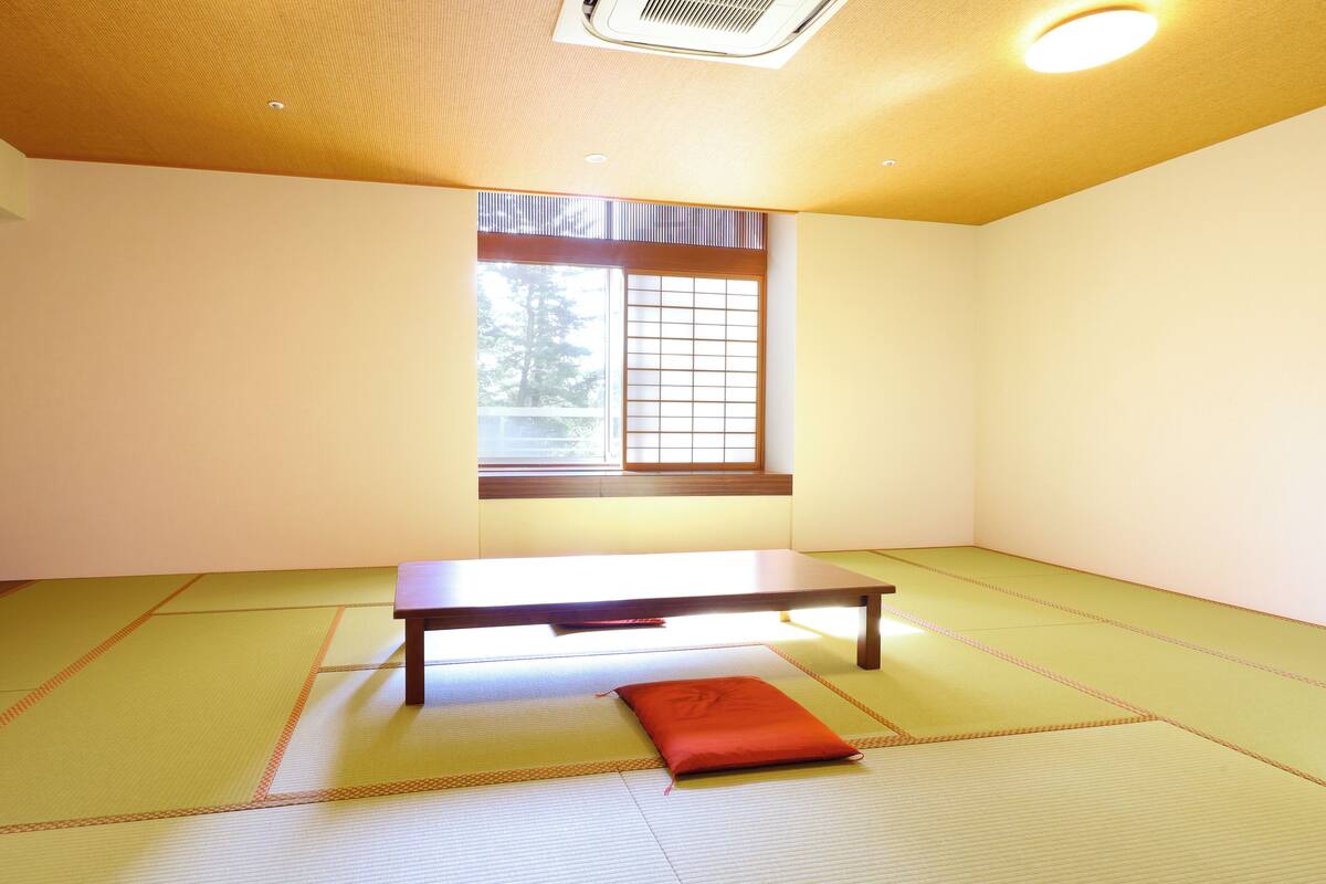 A room with tatami flooring, a low table, and a window with a grid pattern.