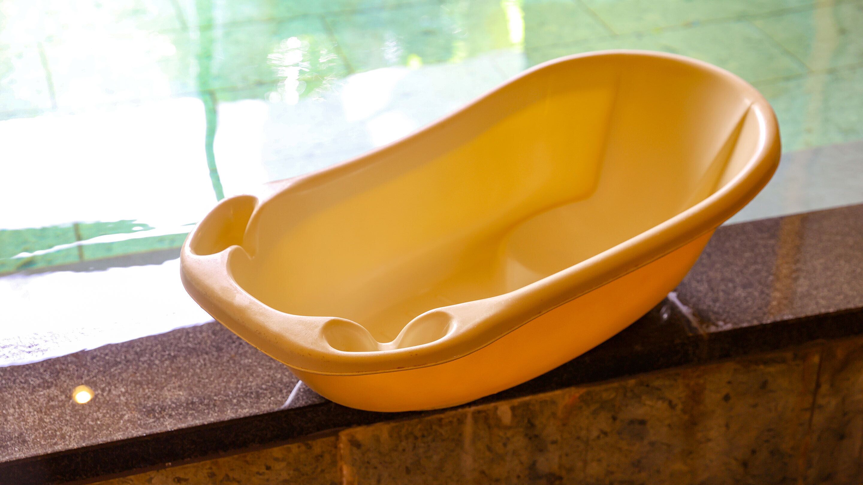 A yellow bowl on a stone ledge near a window.