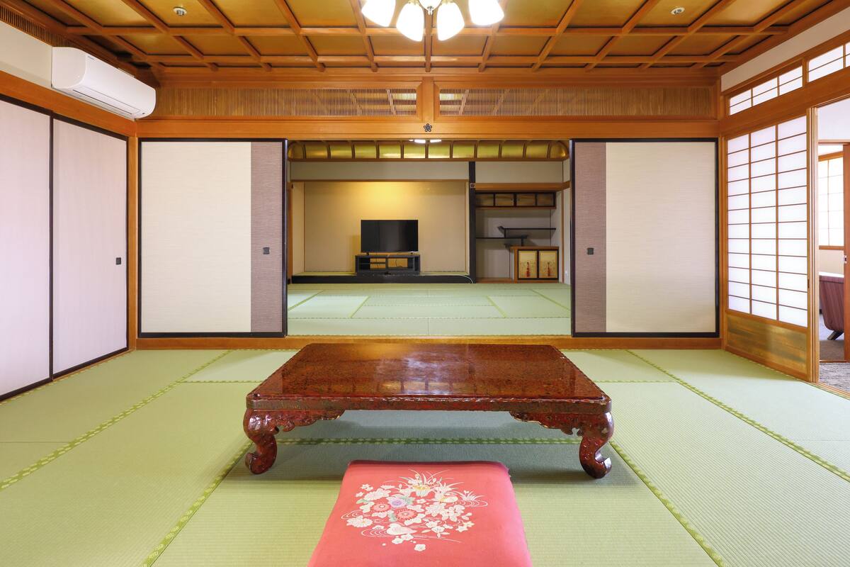 A traditional Japanese room with tatami flooring, a wooden table, and sliding doors.
