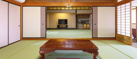 Una habitación japonesa tradicional con suelo de tatami, una mesa de madera y puertas correderas.