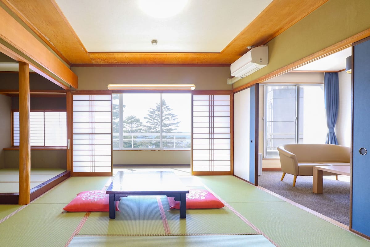 A traditional Japanese room with tatami flooring, a low table, and sliding doors.