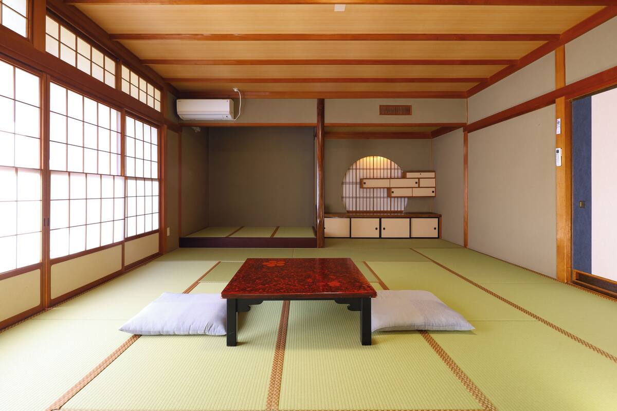 A traditional Japanese room with tatami flooring, a low table with cushions, sliding doors, and a built-in cabinet.