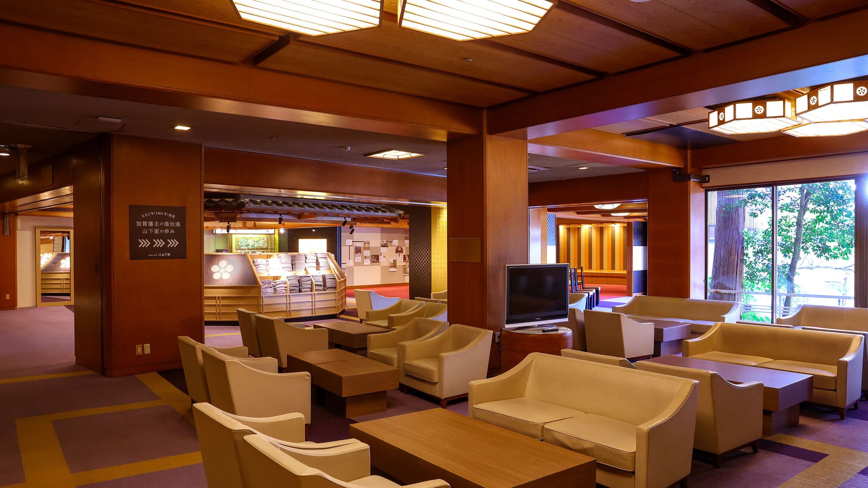 A hotel lobby with seating areas, a television, and a display of local crafts.