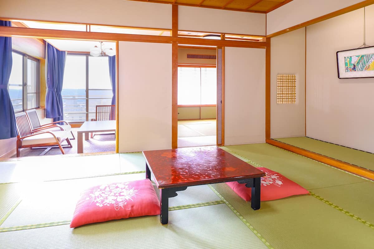 A traditional Japanese room with tatami flooring, a low table, and a view through a sliding door.