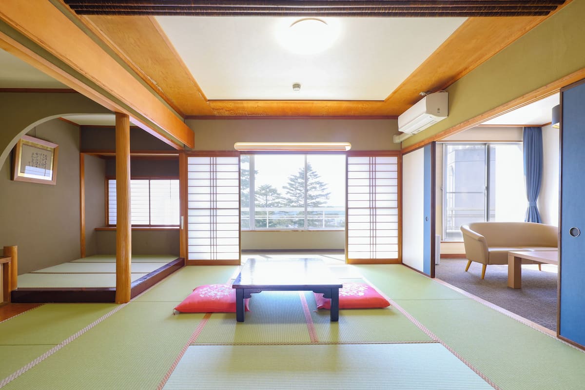A traditional Japanese room with tatami flooring, a low table, and sliding doors.