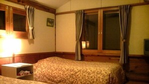 Une chambre d’hôtel avec deux lits, une table de chevet, une fenêtre avec des rideaux et un tableau accroché au mur.