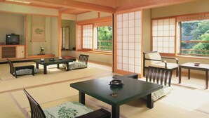 Une pièce de style japonais traditionnel, avec un sol recouvert de tatamis, des portes coulissantes et une petite table basse entourée de coussins.