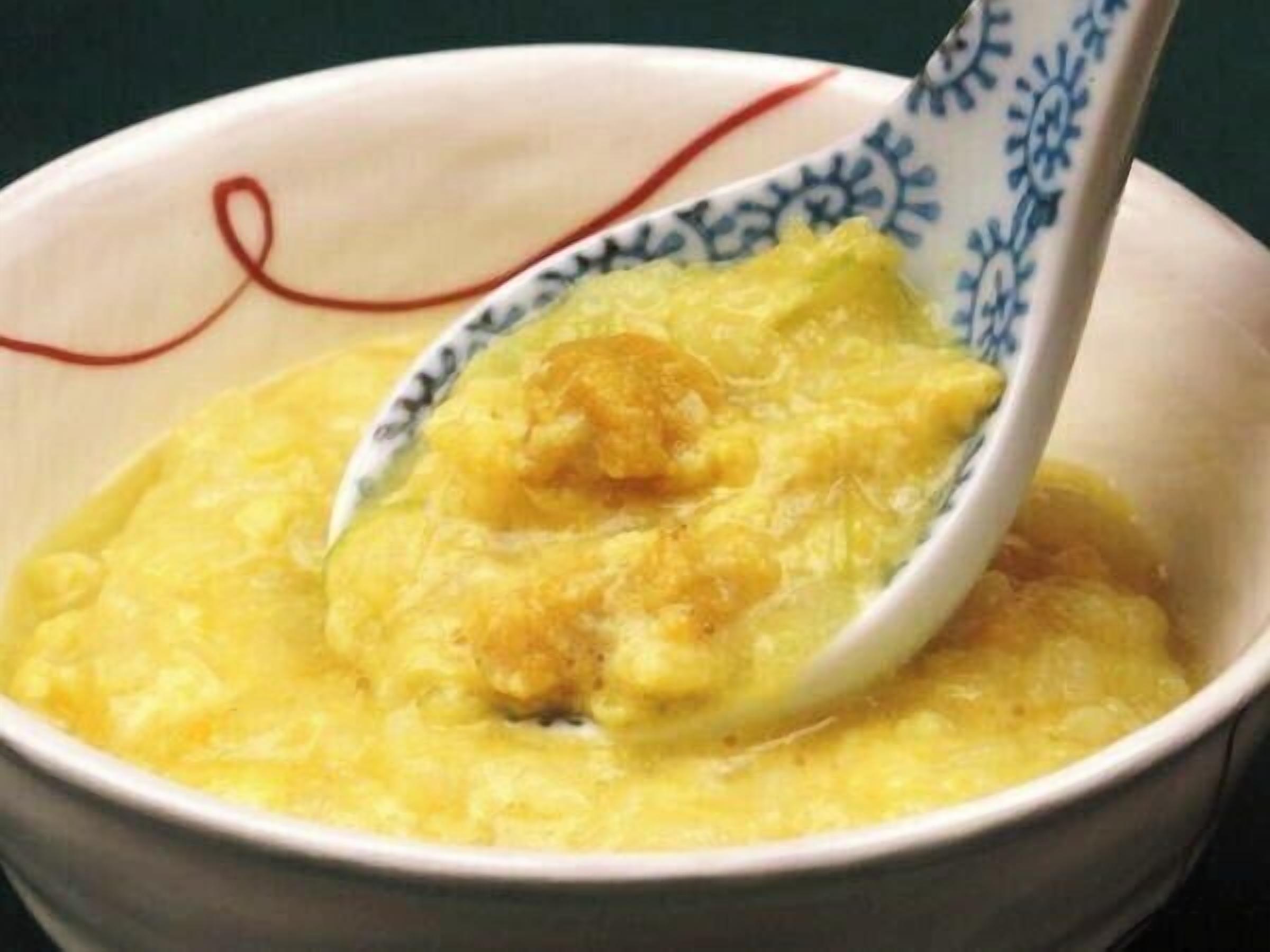 A bowl of yellow food with a spoon.