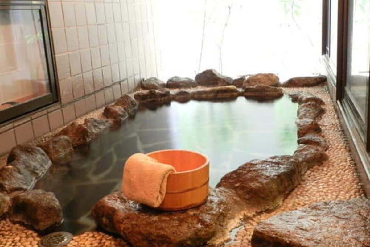 A hot spring bath with a wooden bench and a towel, surrounded by rocks.