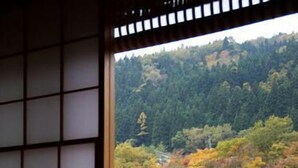 Une pièce avec vue sur une colline boisée, un paravent shoji et une lanterne japonaise traditionnelle en papier.