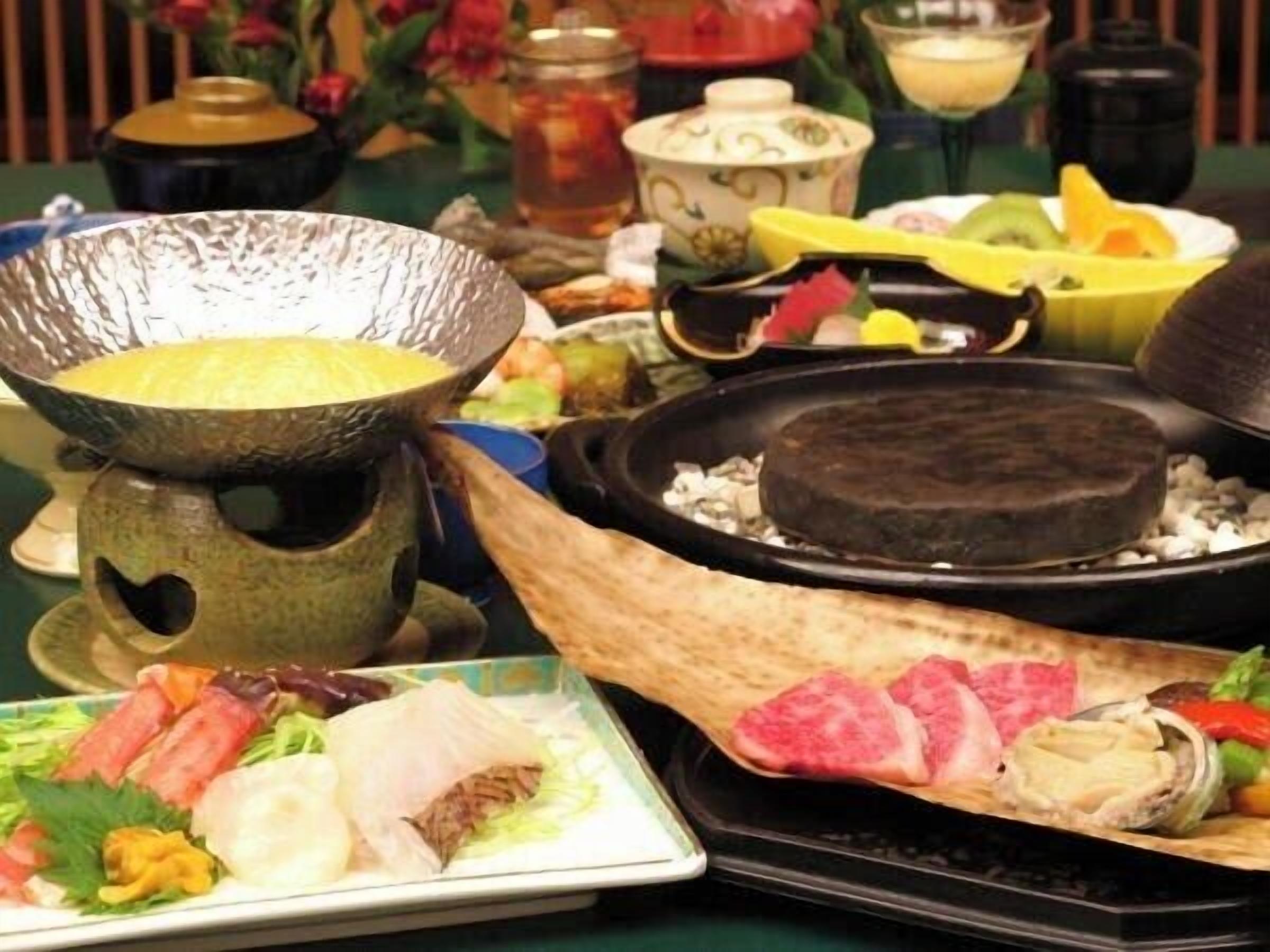 Een traditionele Japanse maaltijdopstelling met een hete pot, een grill en diverse gerechten, waaronder sashimi en groenten.