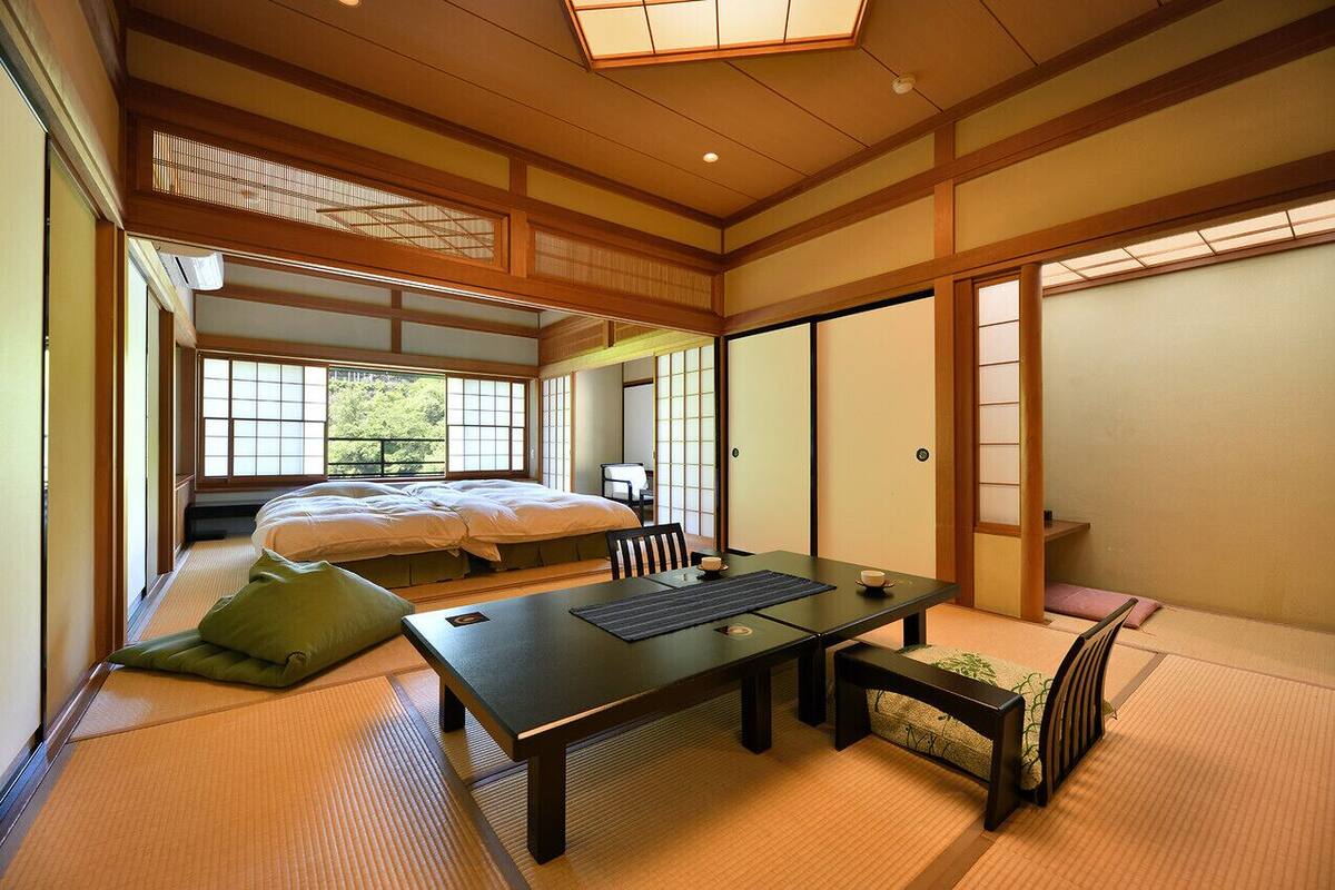 A traditional Japanese-style room with tatami flooring, a low table, and a bed with futon bedding.